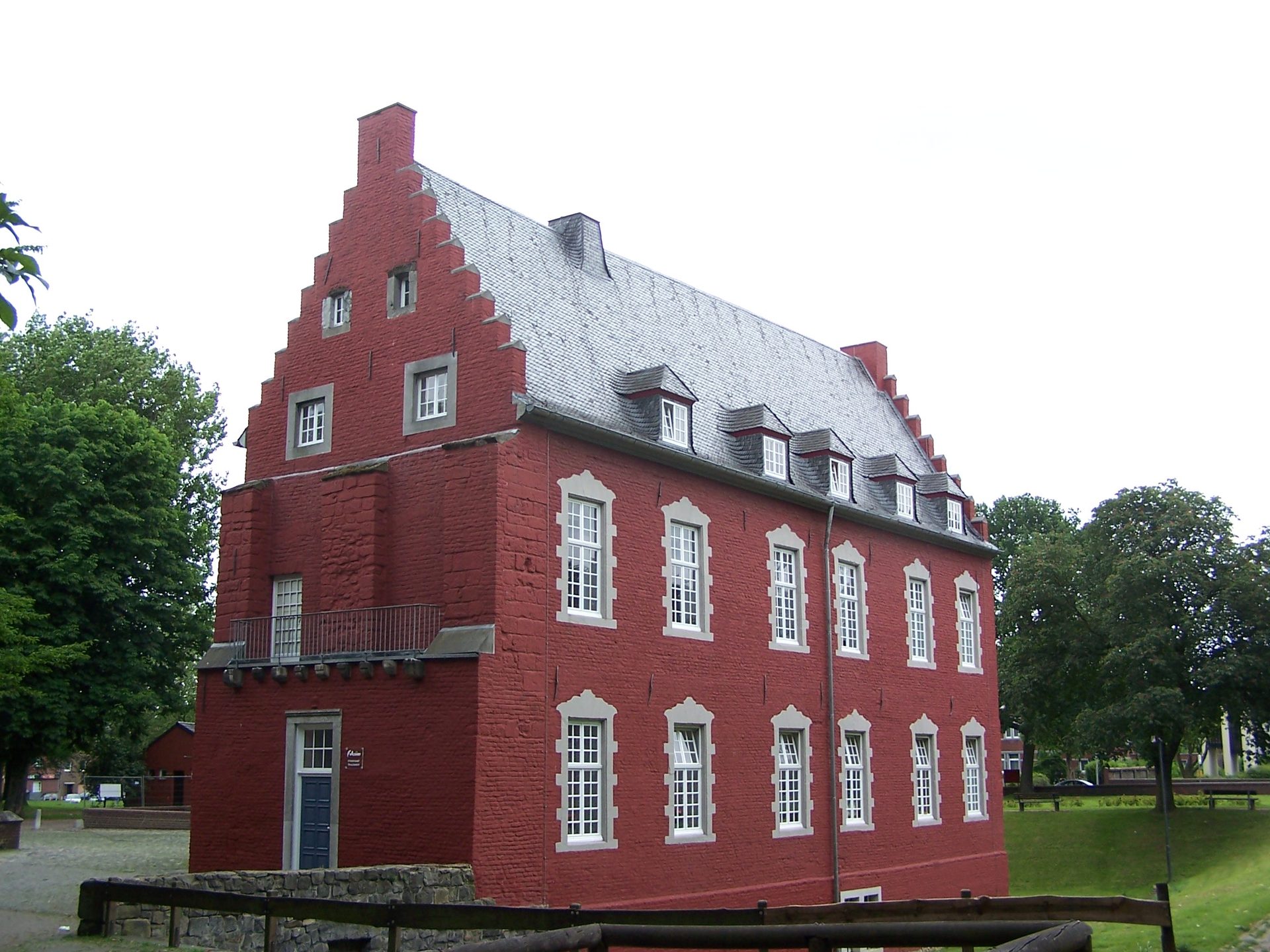 Burg Alsdorf, das rote Backstein-Herrenhaus mit Staffelgiebeln und Schieferdach im Grünen der Innenstadt