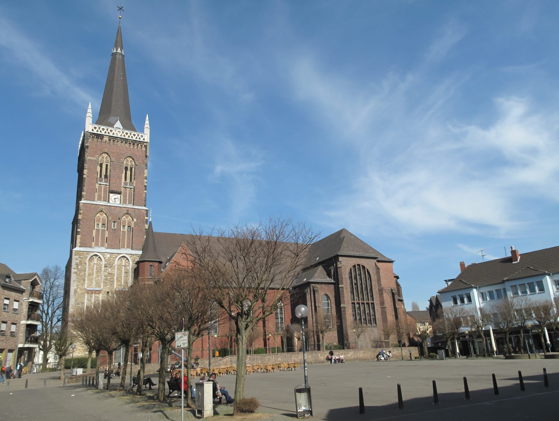 Marktkirche St. Peter und Paul in Eschweiler, die gotische Backsteinkirche mit hohem Spitzturm über dem Marktplatz unter blauem Himmel