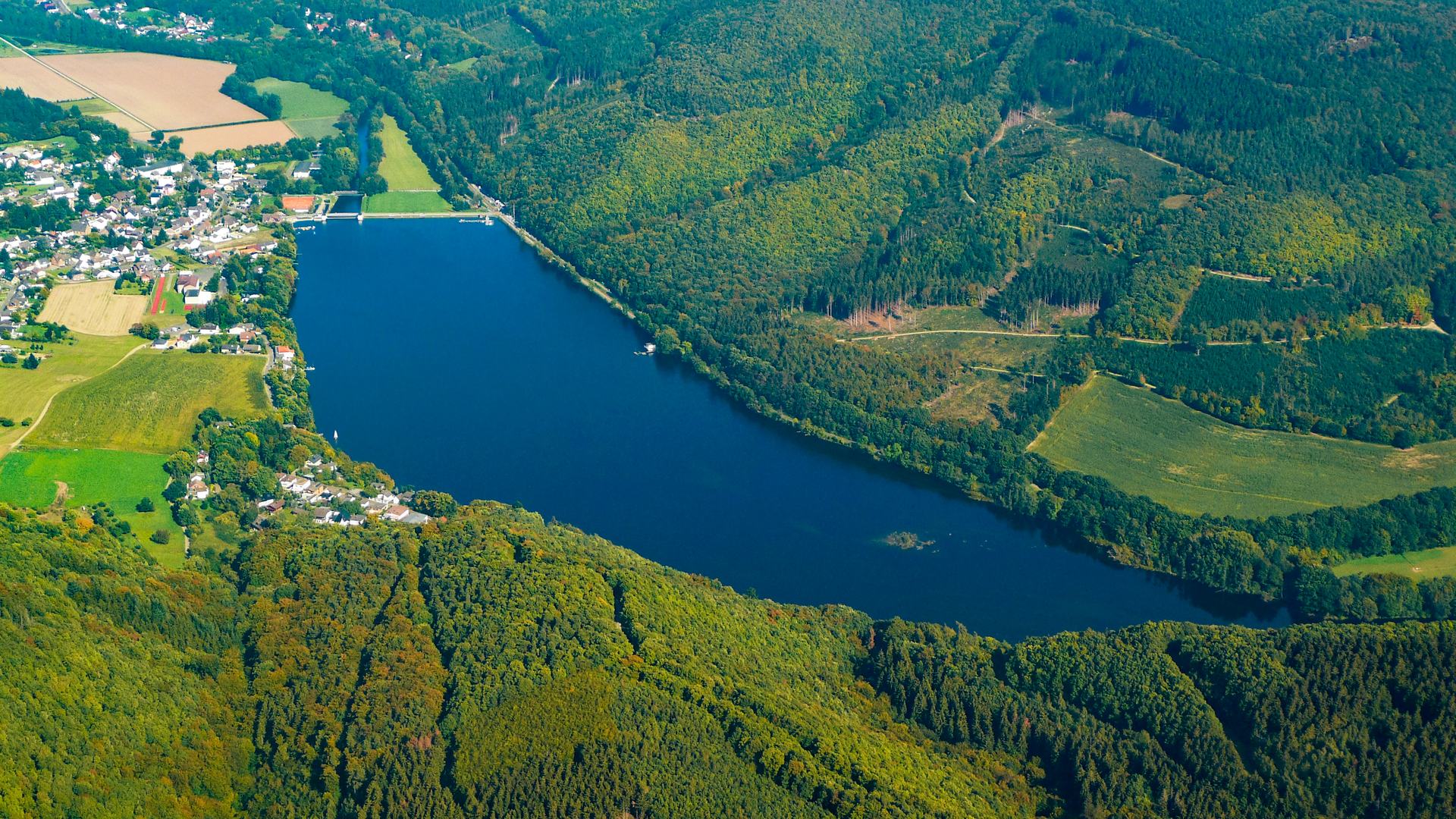 Luftaufnahme des Stausees Obermaubach im Rurtal bei Kreuzau, der von bewaldeten Höhen umgebene See mit dem Ort Obermaubach am Ufer